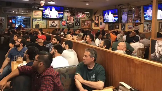 A large crowd at Straw Hat Pizza watching sports on TV screens
