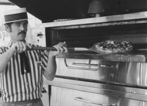 Cook taking pizza out of oven in 1965