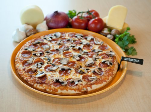 A beautiful mushroom and pepperoni pizza next to onions, tomatoes, cheese and other ingredients