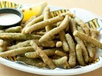 A plate of tasty green bean crispers served with a side of ranch dressing
